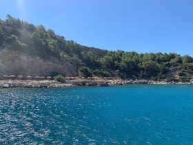A stunning view of a serene coastline with clear turquoise waters and beach umbrellas, perfect for a relaxing day by the sea.