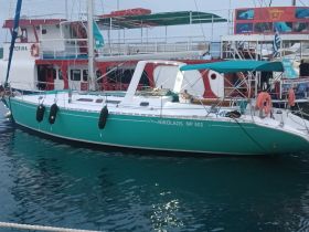 A beautiful turquoise yacht named 'Nikolaos' docked in calm waters, showcasing its sleek design and inviting atmosphere.