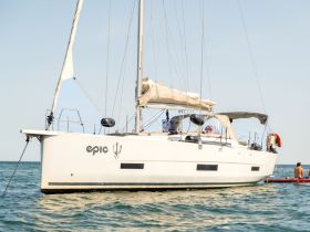 A beautiful sailboat named 'Epic' is anchored in clear waters, with guests enjoying kayaking nearby — perfect for adventurous outings on the water.