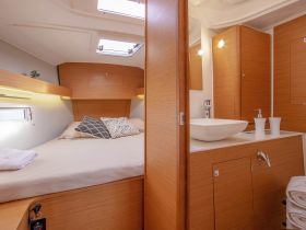 A cozy interior view of a boat cabin featuring a comfortable bed and a modern bathroom setup, perfect for relaxing during your nautical adventures.