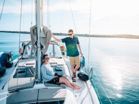 A couple enjoys a sunny day on a sailboat, capturing the essence of relaxation and adventure on the water.