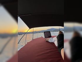 A serene sunset view from the deck of a boat, showcasing a guest relaxing and enjoying the tranquil waters — perfect for unwinding after a day of adventure.