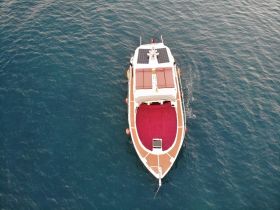 Aerial view of a sleek yacht cruising through deep blue waters, showcasing its elegant design and spacious deck.
