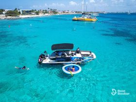A vibrant scene of guests enjoying snorkeling and swimming near a boat in crystal-clear turquoise waters, perfect for a fun day on the water.