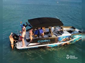 A lively group enjoys a private charter on a boat, celebrating in the water and waving for the camera — perfect for fun-filled days on the sea.