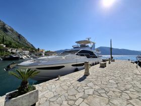 A stunning yacht docked at a picturesque marina, surrounded by lush hills and clear blue skies — perfect for luxury getaways and coastal adventures.