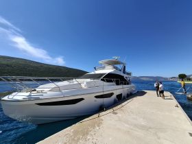 A luxurious yacht docked at a harbor with guests engaging in conversation, showcasing the perfect setting for a day on the water.
