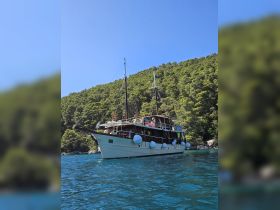 A stunning view of a yacht anchored in clear turquoise waters, surrounded by lush greenery — perfect for exploring scenic coastal destinations.