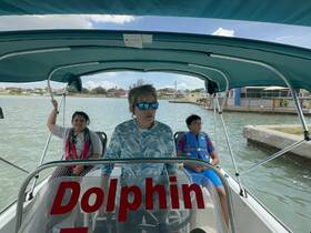 A family enjoys a boat ride, ready for an exciting dolphin encounter. The vibrant atmosphere and scenic backdrop make it a perfect day on the water.