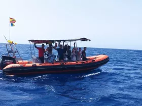 A lively group waves from their boat, enjoying a fun day on the ocean — perfect for group outings and adventures at sea.