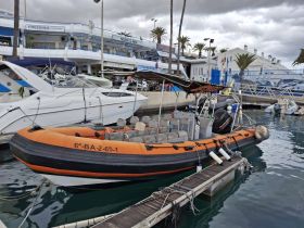 A vibrant orange speedboat docked at a marina, showcasing its sleek design and spacious seating, perfect for thrilling water adventures.
