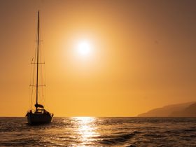 A stunning silhouette of a sailboat against a vibrant sunset, creating a picturesque scene perfect for romantic getaways or serene sailing adventures.