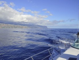 A scenic view of a boat cruising through deep blue waters, with a stunning coastal landscape in the background — perfect for showcasing maritime adventures.