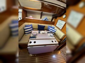 Cozy interior of a boat featuring a dining area with elegant table settings and comfortable seating, perfect for intimate meals on the water.