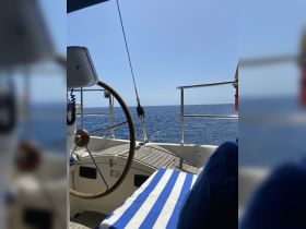 A view from the helm of a sailboat, showcasing the steering wheel and seating area, perfect for navigating the open waters.