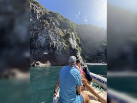 A group of guests enjoys a scenic boat ride, taking in the stunning waterfall cascading down the cliffs — a perfect adventure for nature lovers.