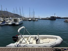 A sleek speedboat docked in a marina, surrounded by various other vessels and a picturesque backdrop of the harbor.