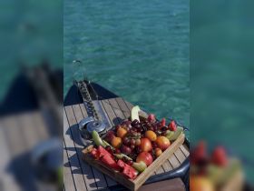 A beautifully arranged platter of fresh fruit sits on the deck of a boat, perfect for enjoying a refreshing snack while cruising on clear waters.