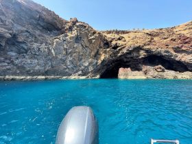 A stunning view of a rocky coastline and cave entrance, surrounded by vibrant turquoise waters — perfect for exploring hidden gems by boat.