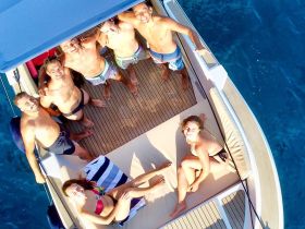 A lively group enjoys a fun day on the boat, capturing the moment with smiles and sunbathing — perfect for summer adventures on the water.
