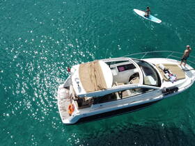 An aerial view captures a stunning boat with guests enjoying paddleboarding in crystal-clear waters — perfect for summer adventures and water sports.