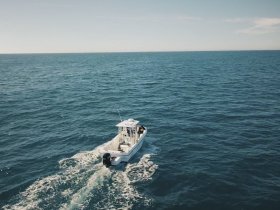 Aerial view of a sleek speedboat cruising through open waters, showcasing the vessel's design and the beauty of the ocean.