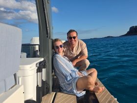 A happy couple enjoys their time on a boat, smiling against a backdrop of clear blue waters — perfect for romantic getaways or fun-filled adventures on the sea.