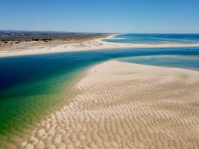 A stunning aerial view of a picturesque coastline featuring golden sands and turquoise waters, perfect for showcasing the beauty of beach destinations.