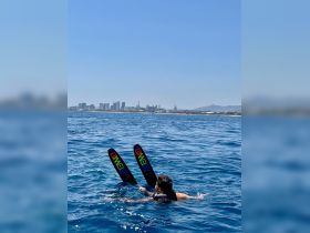 A person enjoys water skiing in the open sea with a stunning city skyline in the background, showcasing the thrill of on-water activities.