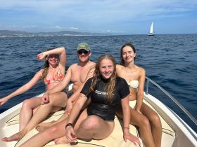 A group of friends enjoys a sunny day on the water, relaxing on the bow of a boat — perfect for summer adventures and memorable outings.