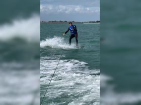 A thrilling moment captured as a wakeboarder carves through the waves, showcasing the excitement of water sports on a sunny day.