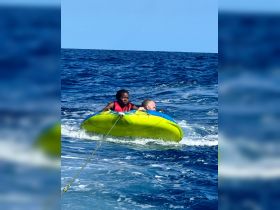 A thrilling moment as a couple enjoys tubing in the open sea, showcasing the excitement of water sports and adventure on the water.