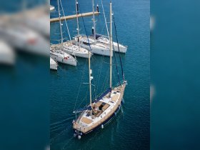A stunning aerial view of a sailboat docked in clear turquoise waters, showcasing its elegant design among other vessels in the marina.