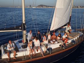 A lively group enjoys a sailing experience on a yacht, capturing moments of joy and camaraderie against a stunning ocean backdrop.