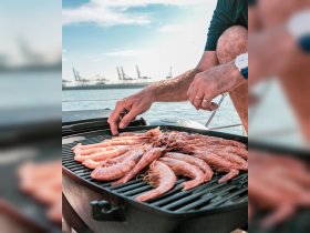 A close-up of shrimp grilling on a barbecue aboard a boat, showcasing delicious onboard dining options for a perfect day on the water.