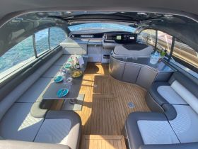 A stylish interior view of a luxury boat cabin featuring comfortable seating and a dining area, perfect for enjoying meals while cruising on the water.