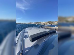 A stunning view of a yacht's deck, showcasing a spacious sunbathing area with a backdrop of a picturesque coastal town. Ideal for luxury cruising and relaxation on the water.