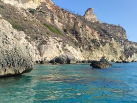A stunning view of rocky cliffs and clear turquoise waters, showcasing the natural beauty of the coastline — perfect for exploring by boat.