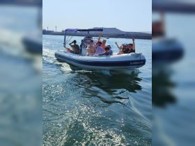 A lively group enjoys a fun day on the water aboard a boat, waving and celebrating together — perfect for family outings or group adventures.