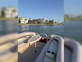Interior view of a comfortable pontoon boat seating area, featuring plush lounge seating and a table, perfect for relaxing on the water.