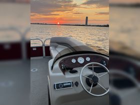 A serene view of the helm inside a pontoon boat, with a stunning sunset reflecting on the water — perfect for evening cruises.