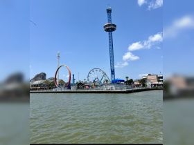 A vibrant view of an amusement park featuring a ferris wheel and roller coaster, set against a clear blue sky — a perfect destination for family fun and entertainment.