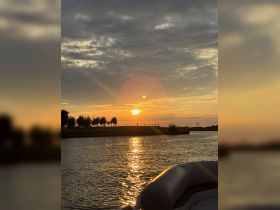 A serene sunset view over the water, with the silhouette of a boat in the foreground, creating a picturesque scene perfect for evening cruises.