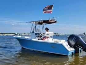 A person navigates a sleek blue boat on calm waters, showcasing a perfect day for boating adventures.