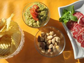 A delightful spread of snacks featuring guacamole, chips, and assorted nuts, perfect for enjoying on a boat trip or gathering.