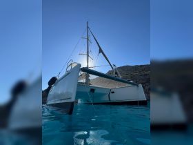 A stunning view of a catamaran sailing through crystal-clear waters, showcasing its sleek design against a backdrop of a clear blue sky.