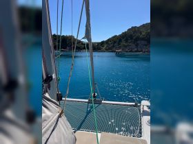 A serene view from the deck of a catamaran, showcasing the tranquil turquoise waters and lush greenery of the coastline — perfect for sailing adventures and exploring hidden coves.