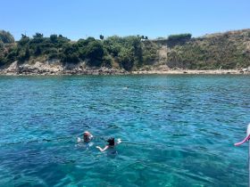 Two children enjoy swimming in the crystal-clear waters near a scenic shoreline, perfect for family beach days and aquatic adventures.