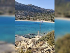 A stunning view of a serene beach in Greece, featuring crystal-clear waters and a picturesque coastline, perfect for a relaxing getaway.