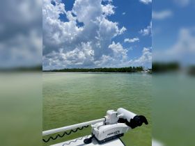 A clear view of a boat's motor and the serene waters under a dramatic sky, perfect for showcasing boating adventures.